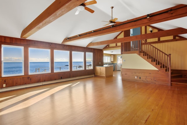 unfurnished living room with a water view, ceiling fan, baseboard heating, beamed ceiling, and light hardwood / wood-style floors