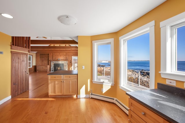 kitchen with beam ceiling, light hardwood / wood-style flooring, a baseboard heating unit, kitchen peninsula, and a water view