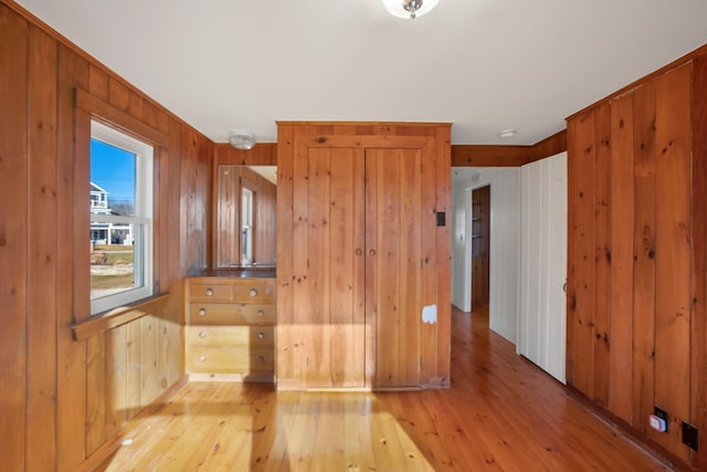 empty room with light wood-type flooring and wood walls