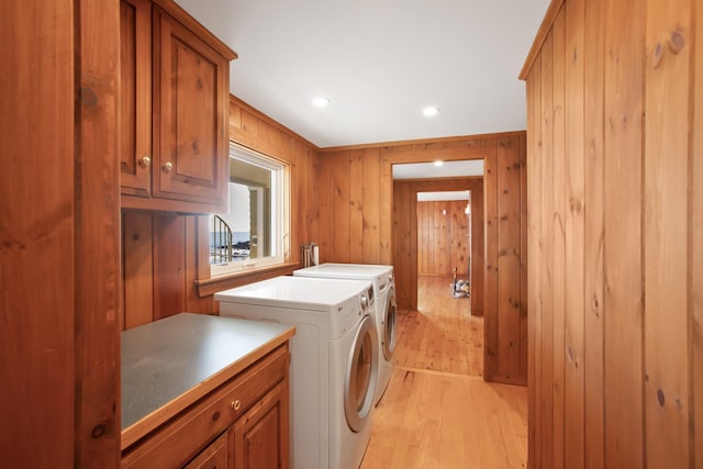 laundry area featuring cabinets, light hardwood / wood-style floors, washer and clothes dryer, and wood walls