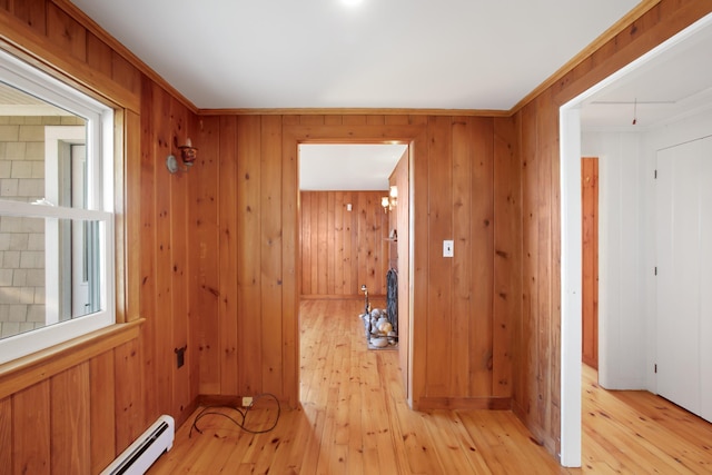 laundry area with a baseboard radiator, wooden walls, and light hardwood / wood-style flooring