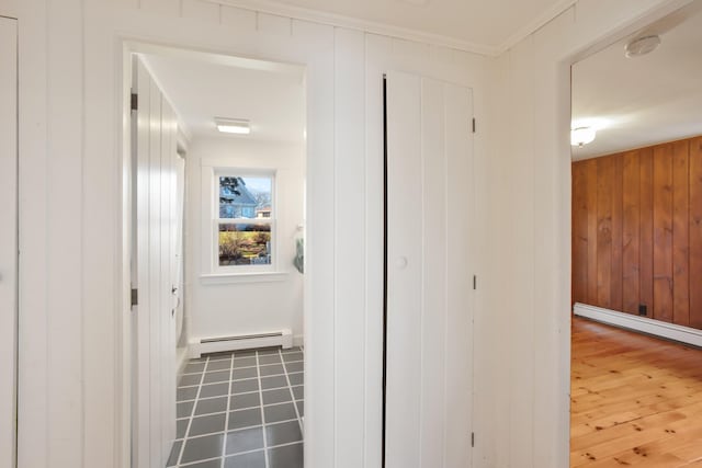 corridor with wood walls, ornamental molding, a baseboard heating unit, and hardwood / wood-style flooring