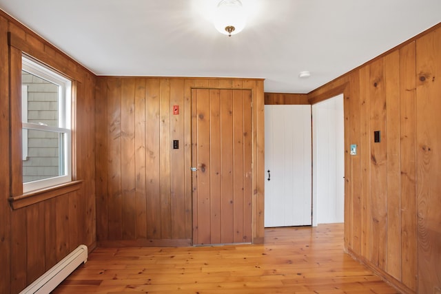 entrance foyer featuring light hardwood / wood-style flooring, wooden walls, and a baseboard radiator