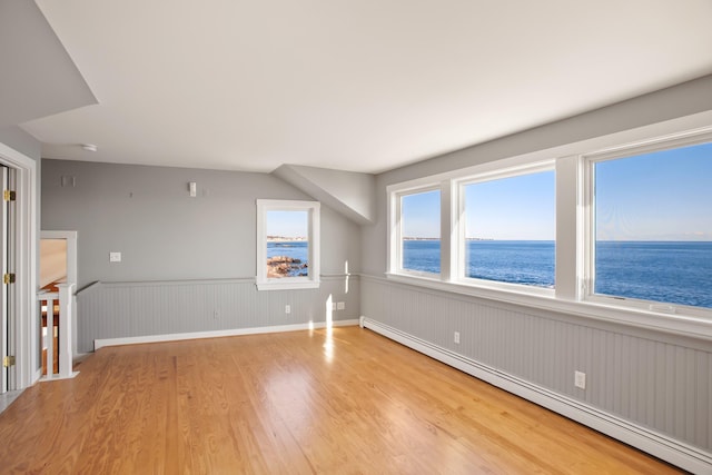 bonus room with light hardwood / wood-style flooring, a water view, and a baseboard heating unit