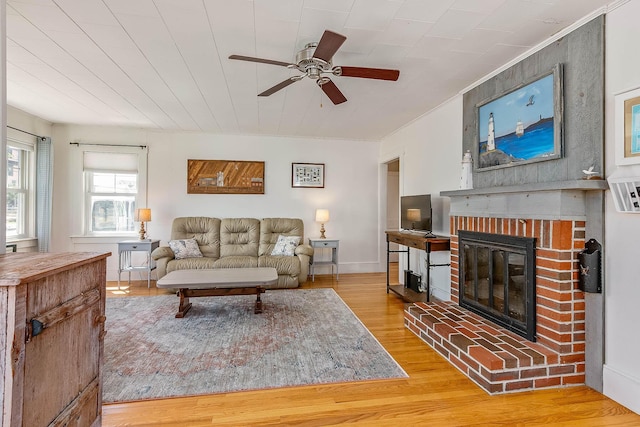 living room with ceiling fan, a fireplace, and light hardwood / wood-style flooring