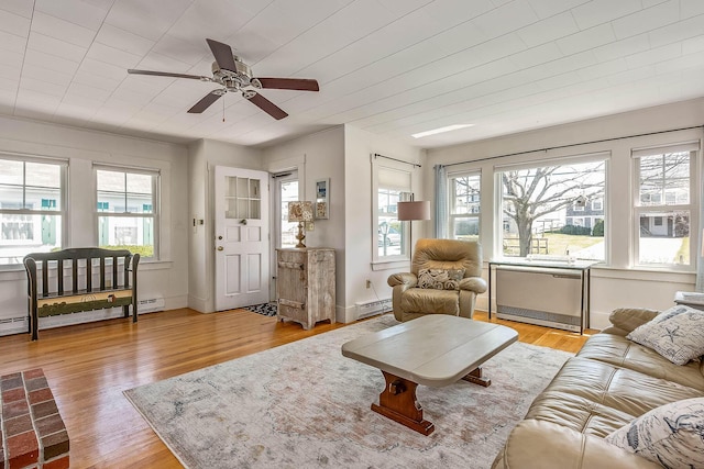 living room with light hardwood / wood-style flooring, a wealth of natural light, a baseboard heating unit, and ceiling fan