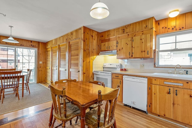 kitchen with light hardwood / wood-style floors, sink, white appliances, and hanging light fixtures