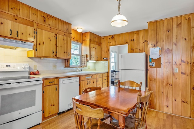 kitchen with light hardwood / wood-style floors, sink, white appliances, and hanging light fixtures