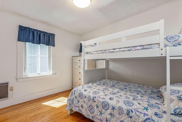 bedroom featuring hardwood / wood-style flooring, ornamental molding, and heating unit