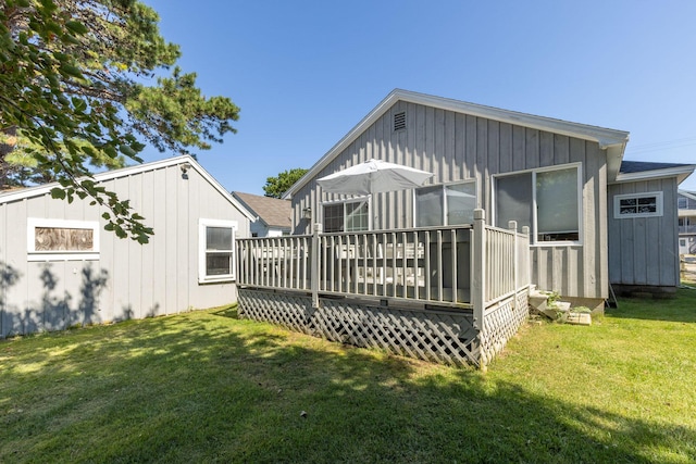 back of property featuring a wooden deck and a yard