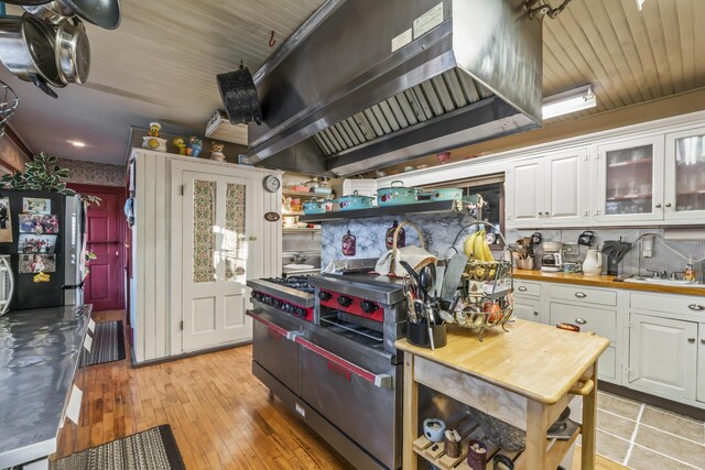 9 Dry Point Dr, Rome, ME 04963 - kitchen featuring white cabinetry, appliances with stainless steel finishes, wall chimney range hood, and light wood-type flooring