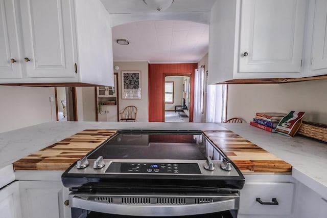 kitchen with white cabinets, wood counters, and electric range