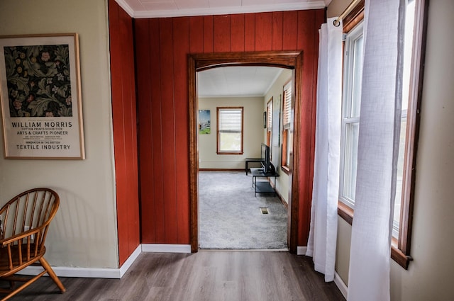 corridor featuring wood walls, ornamental molding, and hardwood / wood-style flooring