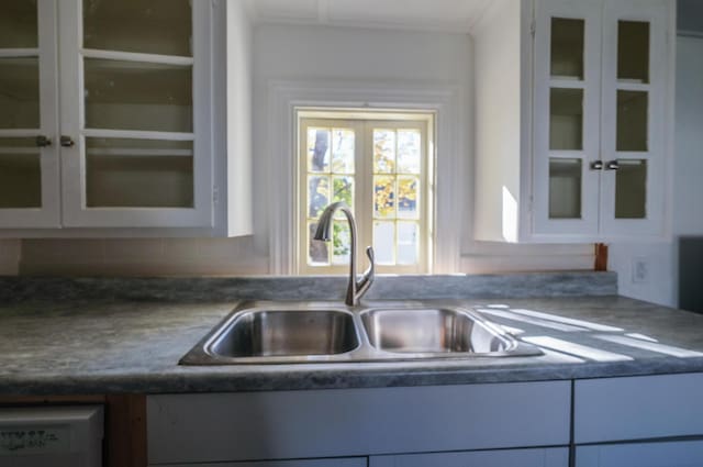 kitchen featuring tasteful backsplash, dishwashing machine, sink, and white cabinets