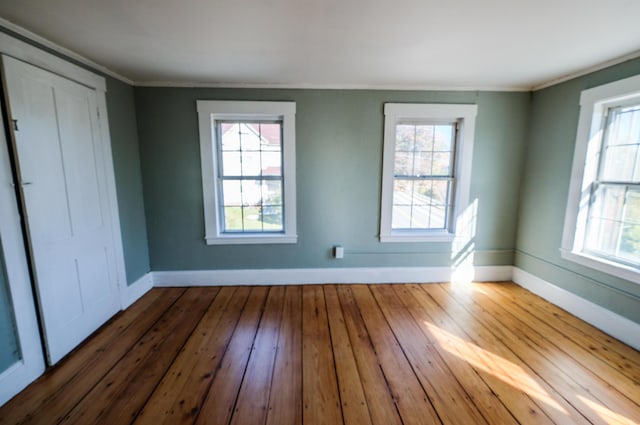 unfurnished room featuring ornamental molding, hardwood / wood-style flooring, and a healthy amount of sunlight