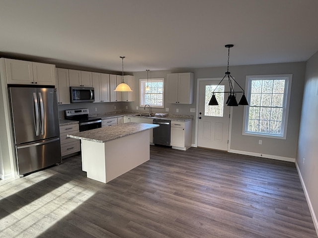 kitchen featuring sink, white cabinetry, decorative light fixtures, a center island, and stainless steel appliances