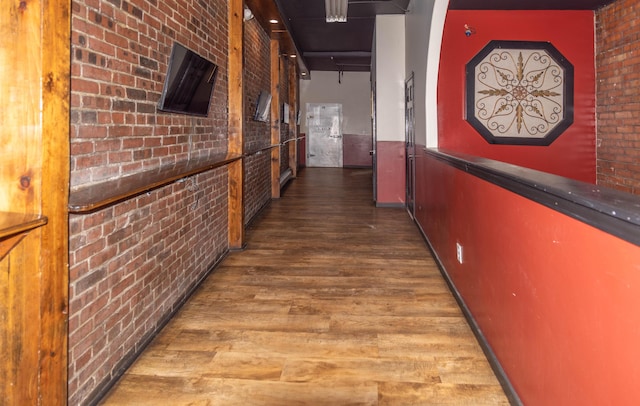 hallway featuring brick wall and hardwood / wood-style flooring