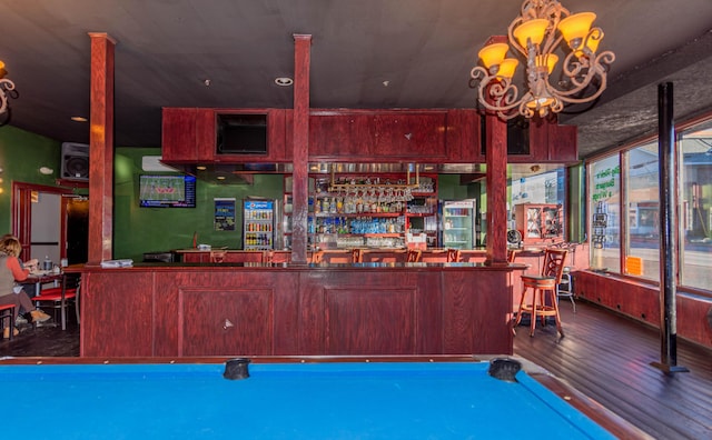 bar featuring dark hardwood / wood-style flooring, an inviting chandelier, and billiards