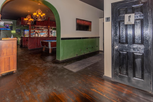 foyer entrance featuring bar area, a chandelier, dark wood-type flooring, and pool table