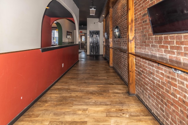 corridor featuring hardwood / wood-style flooring and brick wall