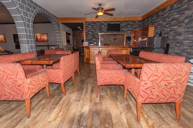 dining space with light hardwood / wood-style floors, ceiling fan, and brick wall