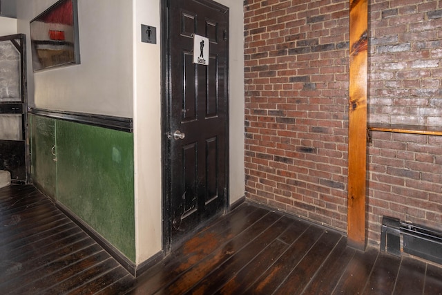 hallway with dark hardwood / wood-style flooring and brick wall