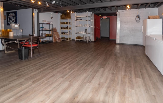 basement featuring wood-type flooring and white refrigerator