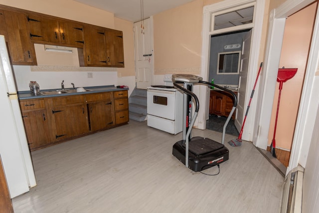 kitchen with light wood-type flooring, white appliances, and sink