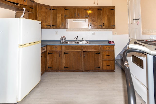 kitchen featuring sink, white appliances, and light wood-type flooring