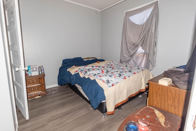 bedroom with dark hardwood / wood-style floors and ornamental molding