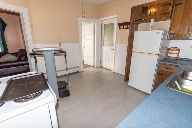 kitchen with hardwood / wood-style floors, white fridge, sink, and a baseboard radiator