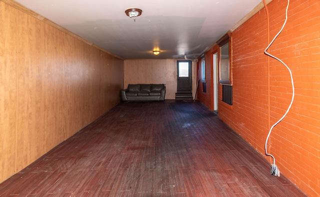 basement with wood walls, dark wood-type flooring, and brick wall