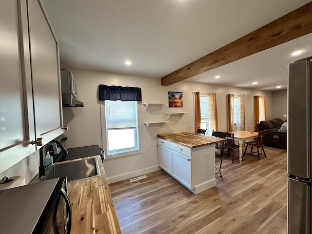 kitchen featuring white cabinets, sink, beamed ceiling, butcher block counters, and stainless steel refrigerator