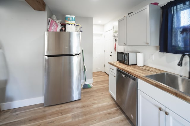 kitchen featuring wooden counters, appliances with stainless steel finishes, white cabinets, and sink