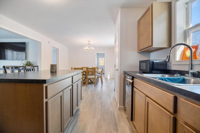 kitchen featuring pendant lighting, sink, light wood-type flooring, a kitchen island, and a chandelier