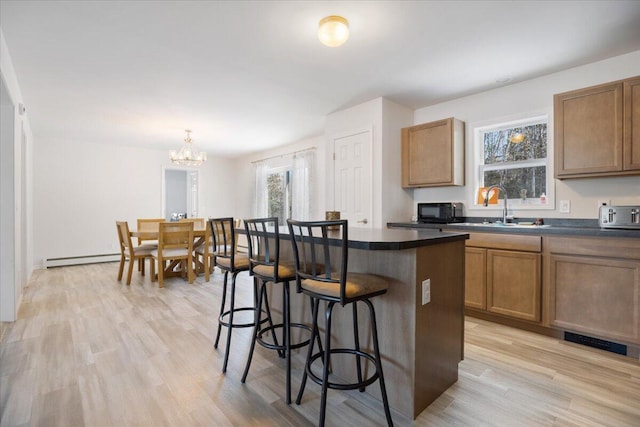 kitchen featuring a center island, sink, light hardwood / wood-style flooring, a breakfast bar area, and a chandelier