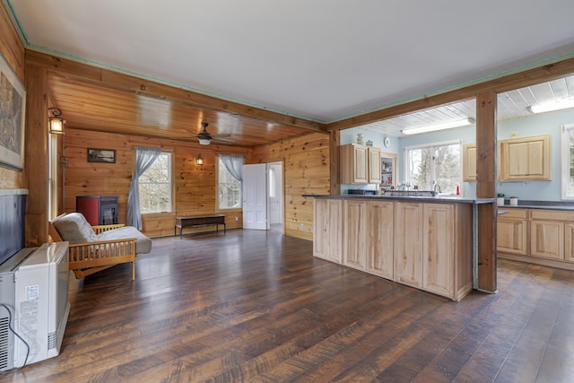 kitchen featuring light brown cabinetry, dark hardwood / wood-style flooring, ceiling fan, and wood walls