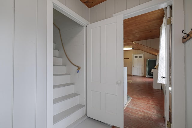 staircase with wood-type flooring, wooden walls, and wood ceiling