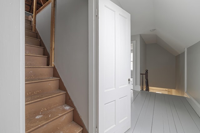 stairway with wood-type flooring and lofted ceiling