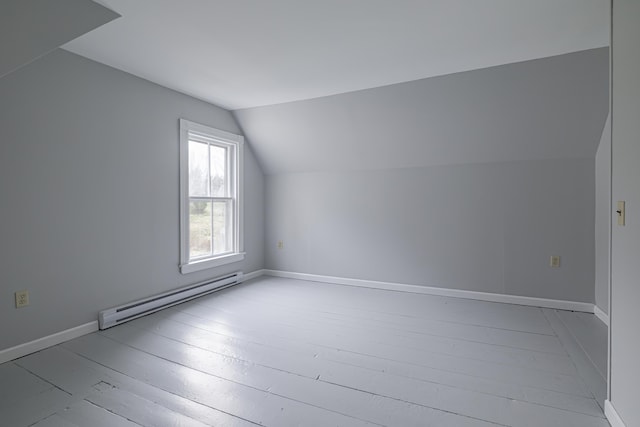 additional living space with light hardwood / wood-style floors, lofted ceiling, and a baseboard heating unit