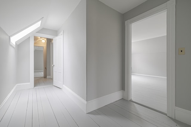 hall with light wood-type flooring and lofted ceiling