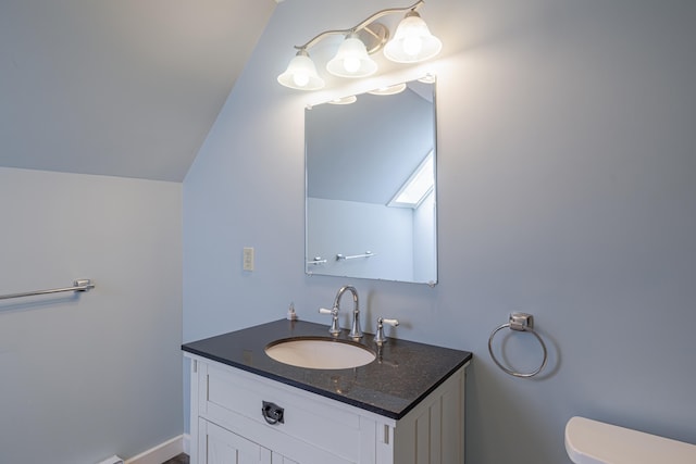 bathroom with vanity, toilet, and lofted ceiling