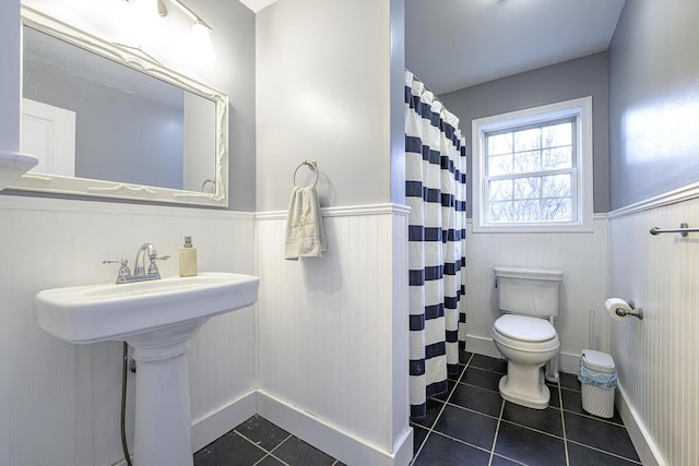 bathroom with toilet, a shower with curtain, and tile patterned floors