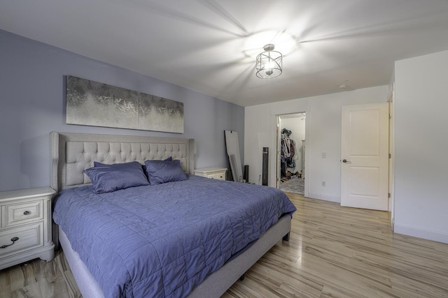 bedroom featuring a spacious closet, a closet, and light wood-type flooring