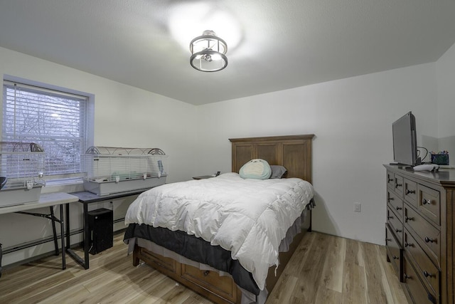 bedroom with light wood-type flooring and a baseboard heating unit