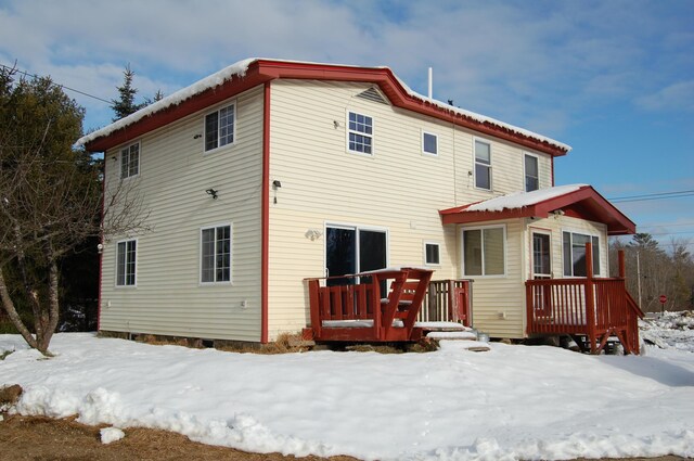 snow covered house featuring a wooden deck