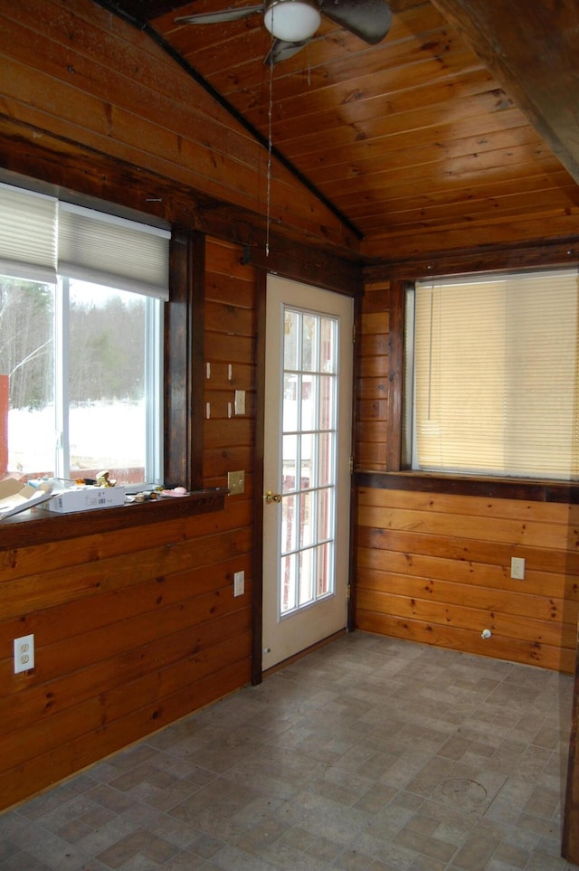 interior space with wooden ceiling, vaulted ceiling, ceiling fan, and wooden walls