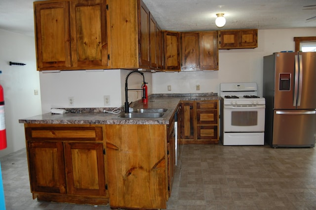 kitchen with a textured ceiling, white gas stove, stainless steel fridge with ice dispenser, and sink