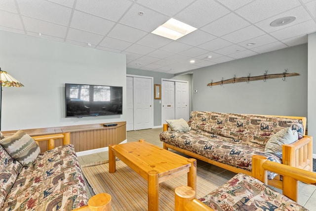 living room featuring a drop ceiling and light tile patterned flooring