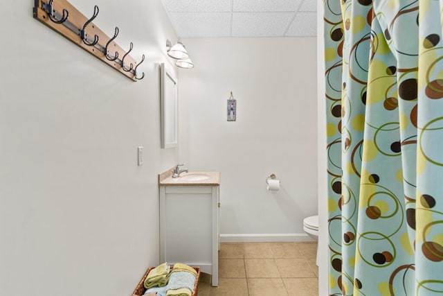 bathroom featuring a paneled ceiling, vanity, tile patterned floors, toilet, and walk in shower